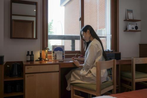 a woman sitting at a kitchen counter looking at her cell phone at Surim Hotel Sokcho by AanK in Sokcho