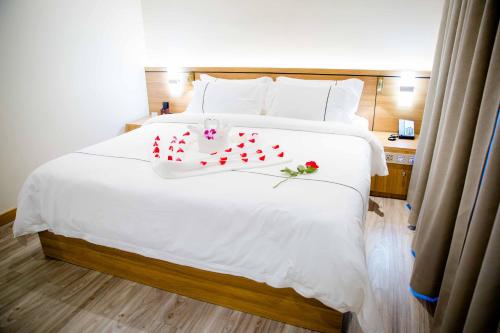 a bedroom with a large white bed with roses on it at Le President Hotel in Phnom Penh