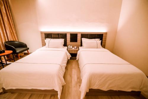 two beds in a hotel room with a chair at Le President Hotel in Phnom Penh