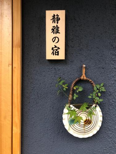 a plate on a wall with a sign and a plant at 静雅の宿 in Kyoto