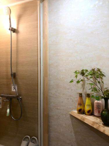 a bathroom with a shower with three bottles on a shelf at 静雅の宿 in Kyoto