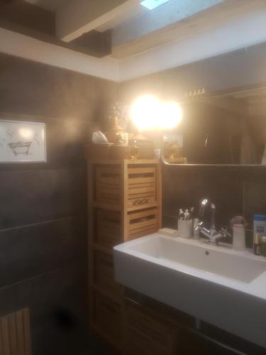 La salle de bains est pourvue d'un lavabo et d'une lumière sur le mur. dans l'établissement Le grenier de Marie, à Saint-Laurent-dʼAigouze