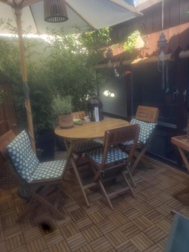 une table et des chaises en bois assises sur une terrasse dans l'établissement Le grenier de Marie, à Saint-Laurent-dʼAigouze