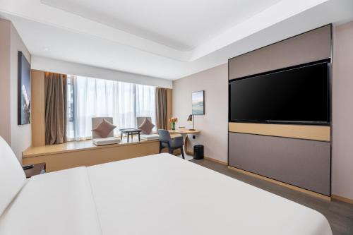 a hotel room with a large bed and a flat screen tv at Atour Hotel Changsha Binjiang Financial Center in Changsha