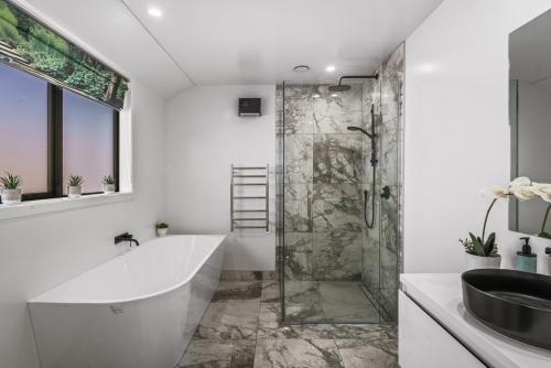a bathroom with a shower and a tub and a sink at Luxury & Modern Living Home & Apartment in Queenstown