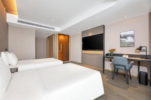 a hotel room with a bed and a desk and a tv at Atour Hotel Changsha Binjiang Financial Center in Changsha