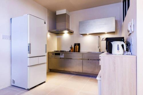 a kitchen with a white refrigerator and a sink at 宮城海岸まで2分 周辺には飲食店多数の北谷エリア セブンヴィレッジ2階 in Chatan