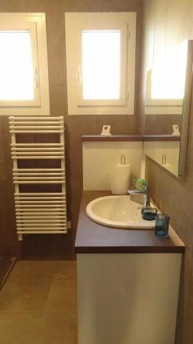 La salle de bains est pourvue d'un lavabo blanc et de 2 fenêtres. dans l'établissement Villa de charme à Taillades avec piscine privée, à Les Taillades