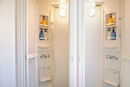 a bathroom with white cabinets and a shower at Japanese House Osaka Sennan Hotel 大阪泉南酒店和築 in Tannowa
