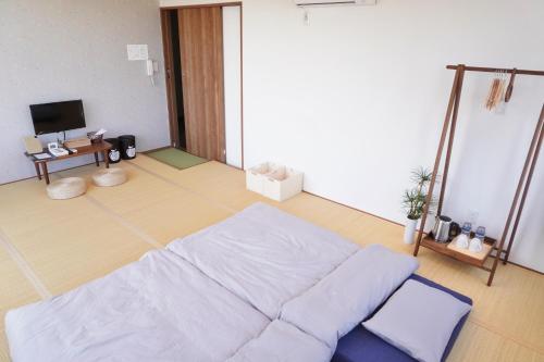 a living room with a white bed and a television at Japanese House Osaka Sennan Hotel 大阪泉南酒店和築 in Tannowa