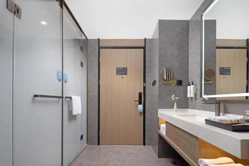 a bathroom with a sink and a shower with a mirror at Wanda Yue Tianjin in Binhai