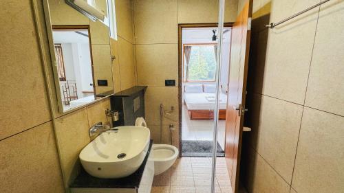 a bathroom with a sink and a toilet and a mirror at Rose Garden at Rajagiri Hospital in Ernakulam