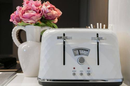 a white toaster sitting next to a vase of flowers at Modern Urban Oasis in the Heart of Chinatown in Sydney