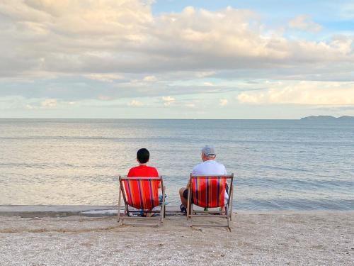 two people sitting in chairs on the beach at Bangsaphan Resort in Bang Saphan