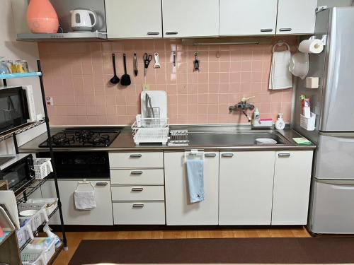 a small kitchen with a sink and a refrigerator at 秋田ゲストハウス　BASE464 in Akita