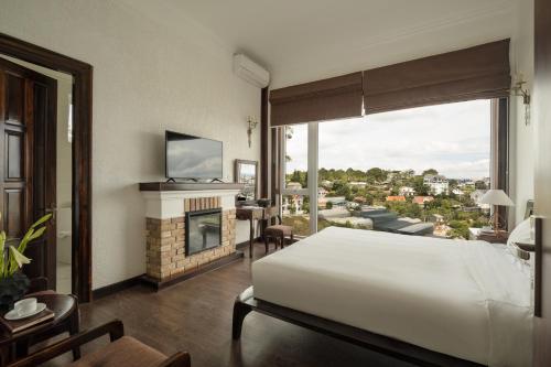 a bedroom with a large white bed and a fireplace at The Manor Villas Da Lat in Xuan An