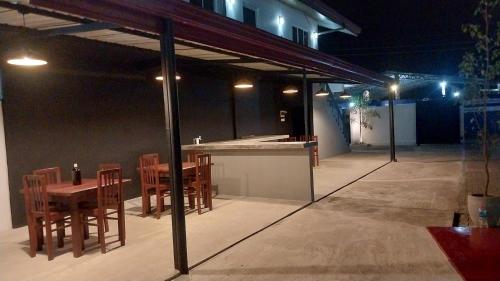 an outdoor bar with wooden chairs and tables at night at Hotel white house mahiyanganaya in Mahiyangana