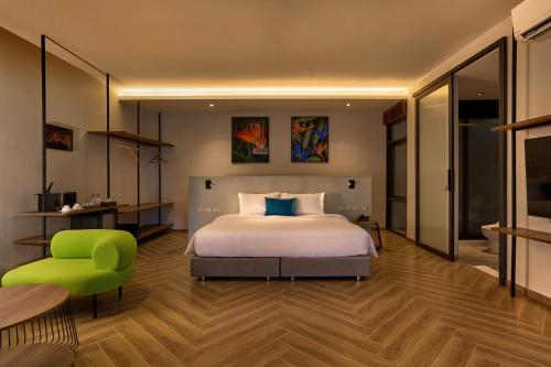 a bedroom with a bed and a green chair at Red Door Samsen Hotel, Bangkok in Bangkok