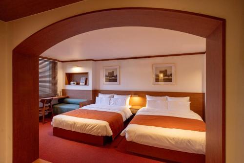 a hotel room with two beds and a chair at Surim Hotel Sokcho by AanK in Sokcho