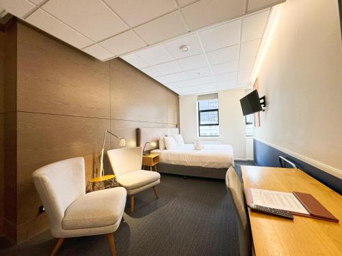 a hotel room with a bed and a desk and chairs at Park Hotel, Lambton Quay in Wellington
