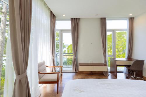 a bedroom with a bed and a desk and windows at The Dream Villa Best Lake View in Xuan An