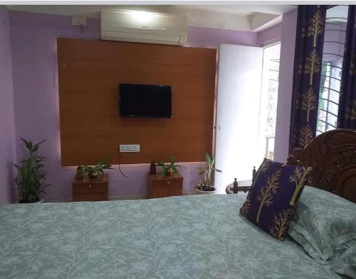 Un dormitorio con una cama con un televisor en la pared. en Aamar Kutir by StayApart, en Siliguri