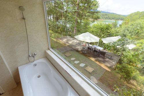 a bath tub in a bathroom with a large window at The Dream Villa Best Lake View in Xuan An