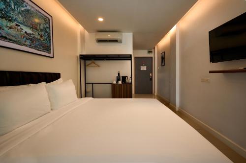a bedroom with a large white bed and a tv at Red Door Samsen Hotel, Bangkok in Bangkok