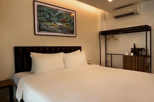 a bedroom with a white bed with a painting on the wall at Red Door Samsen Hotel, Bangkok in Bangkok