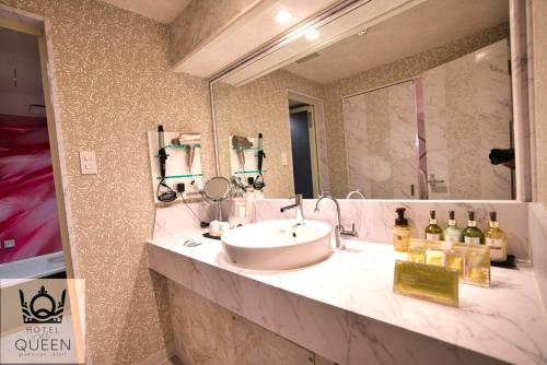 a bathroom with a sink and a large mirror at HOTEL the QUEEN in Toyonaka