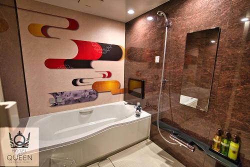 a bathroom with a bath tub and a shower at HOTEL the QUEEN in Toyonaka