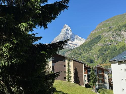 a mountain in the distance with a building and trees at Haus Cervino - luxury apartment in Zermatt
