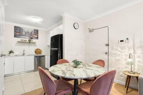 シドニーにある8 mins from Sydney Airport! 1BR with Courtyardのテーブルと椅子のあるキッチンとダイニングルーム