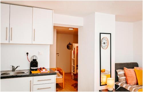 a kitchen with white cabinets and a living room at Family studio apartman in Karlovac