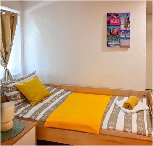 a bedroom with a bed with a yellow and grey blanket at Family studio apartman in Karlovac