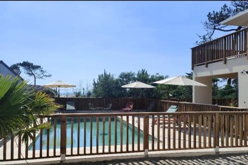une maison avec une piscine et une clôture avec des parasols dans l'établissement Villa Iris jacuzzi vue mer, à Lacanau