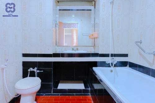 a bathroom with a toilet and a tub and a sink at Bandung Permai Hotel Jember in Jember