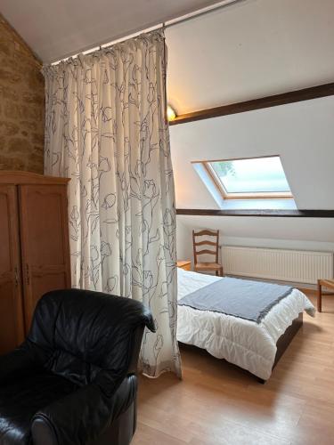 a bedroom with a bed and a chair and a window at Aux 2 cerisiers in Virton