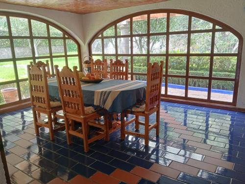 een eetkamer met een tafel, stoelen en ramen bij La Rinconada VIP in Mineral del Chico