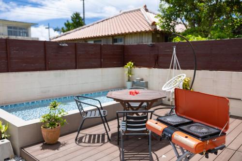 a patio with a table and chairs next to a swimming pool at Hoshitabi Villa Sumuide in Nago
