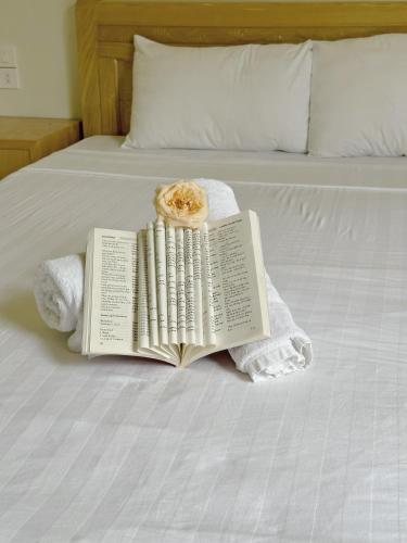 a book with a donut on top of it on a bed at Khách Sạn Tiến Loan in Hòa Bình