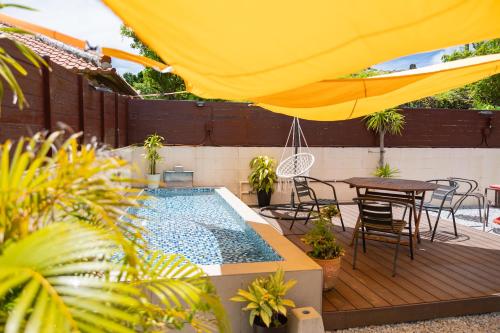a pool with a table and chairs and a yellow umbrella at Hoshitabi Villa Sumuide in Nago