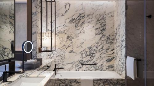 a bathroom with a tub and a marble wall at Renaissance Hangzhou Northeast in Yuhang