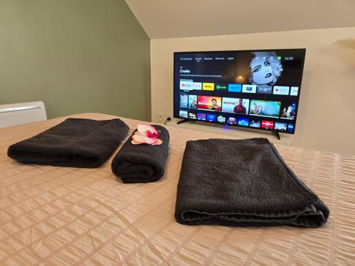 a bedroom with a bed with towels and a tv at Logement de caractère en haute ville de Quimperlé in Quimperlé