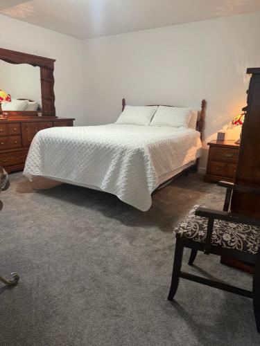 a bedroom with a white bed and wooden furniture at Blarney Place Retreat in Vernon