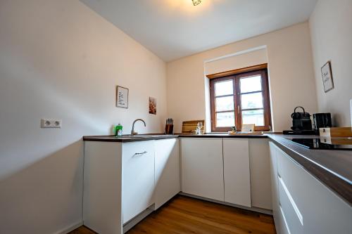 a kitchen with white cabinets and a window at Fachwerk Design-Apartment Sinsheim in Sinsheim