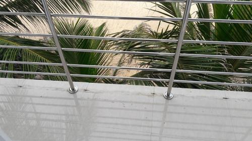 a metal fence with palm trees in the background at Blue Ocean Hotel in Trincomalee