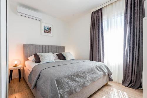 ein weißes Schlafzimmer mit einem Bett und einem Fenster in der Unterkunft Apartman Brodarica Sibenik in Brodarica