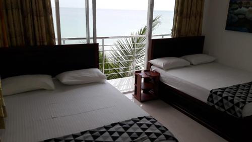 two beds in a room with a balcony at Blue Ocean Hotel in Trincomalee