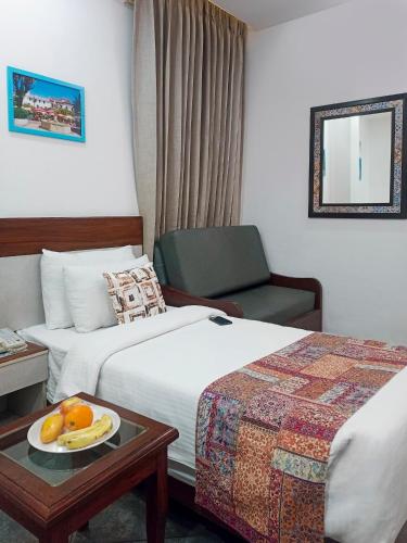 a hotel room with two beds and a table with a plate of fruit at Sterling Marbella Dehradun in Dehradun